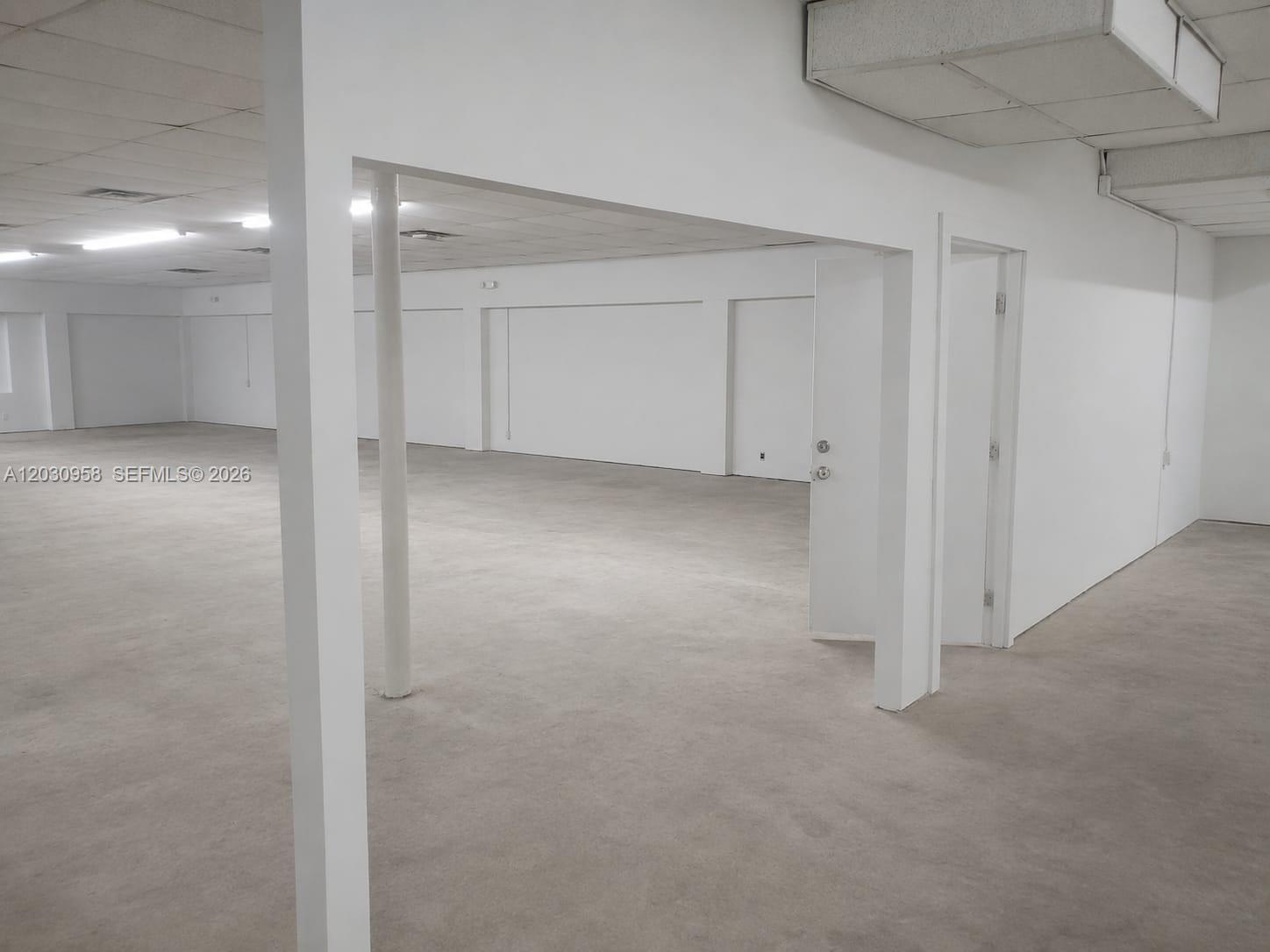 An empty commercial space features white walls, a drop ceiling, and concrete flooring — 5180 NW 17th Ave, Miami FL 33142, MIAMI, FL