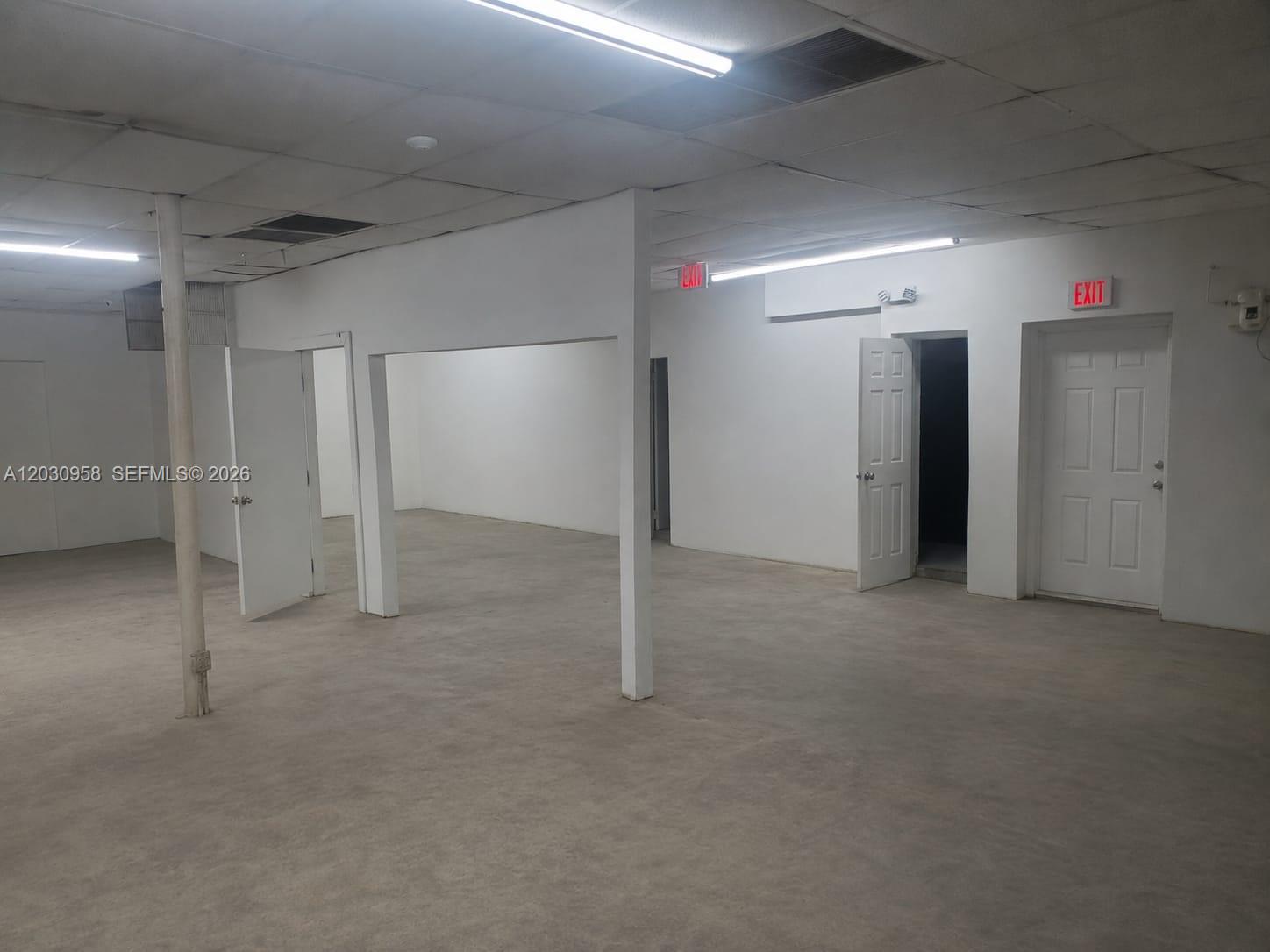 An empty commercial space features white walls, concrete floors, drop ceilings, and multiple doorways — 5180 NW 17th Ave, Miami FL 33142, MIAMI, FL