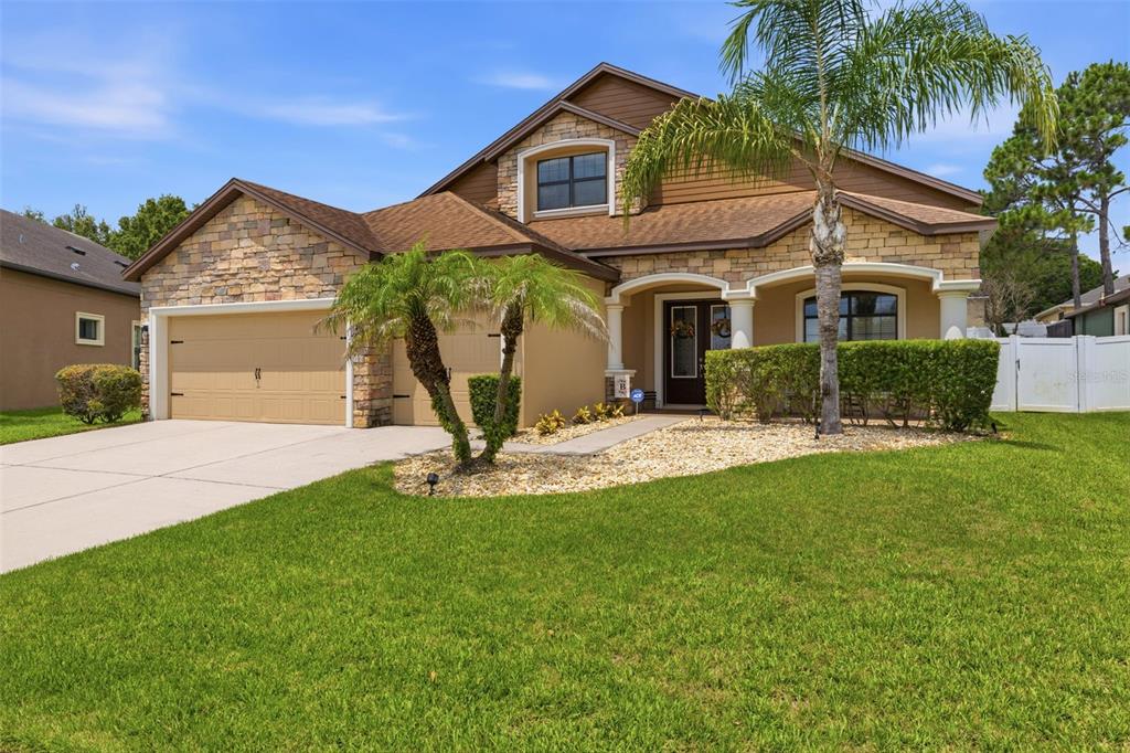 A two-story suburban house with a stone facade, a two-car garage, and a palm tree — 2723 COLEWOOD LANE, DOVER, FL
