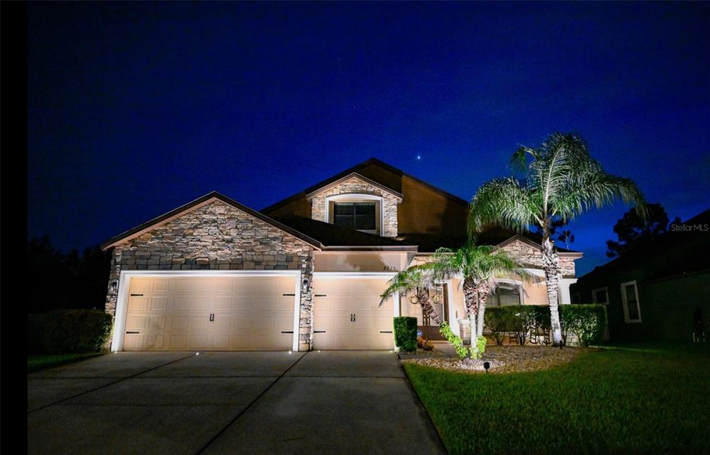 A two-story house with a stone facade, two garage doors, and palm trees at night — 2723 COLEWOOD LANE, DOVER, FL