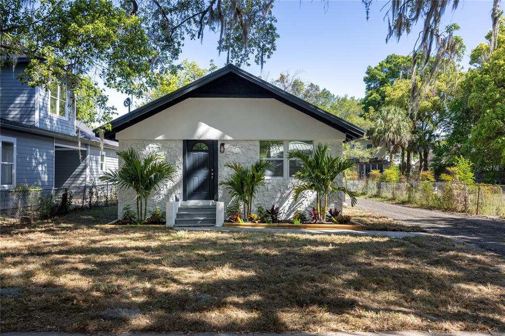 A single-story house with a white stone facade, dark trim, and a front-facing gable roof — 418 NW 3RD AVENUE, GAINESVILLE, FL