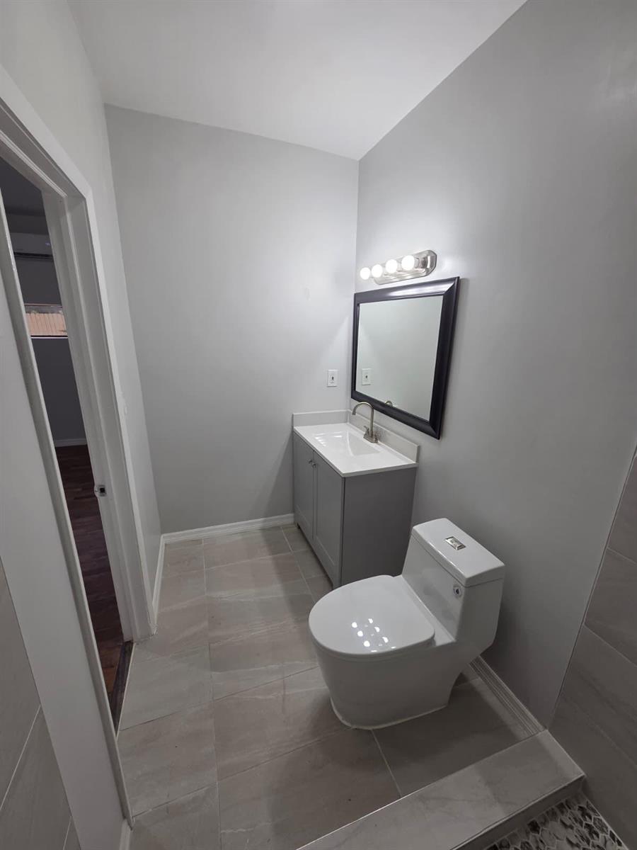 A bathroom features a gray vanity, a black-framed mirror, a toilet, and light gray tile flooring — 31 Edmund Road # 5, West Park FL 33023, WEST PARK, FL