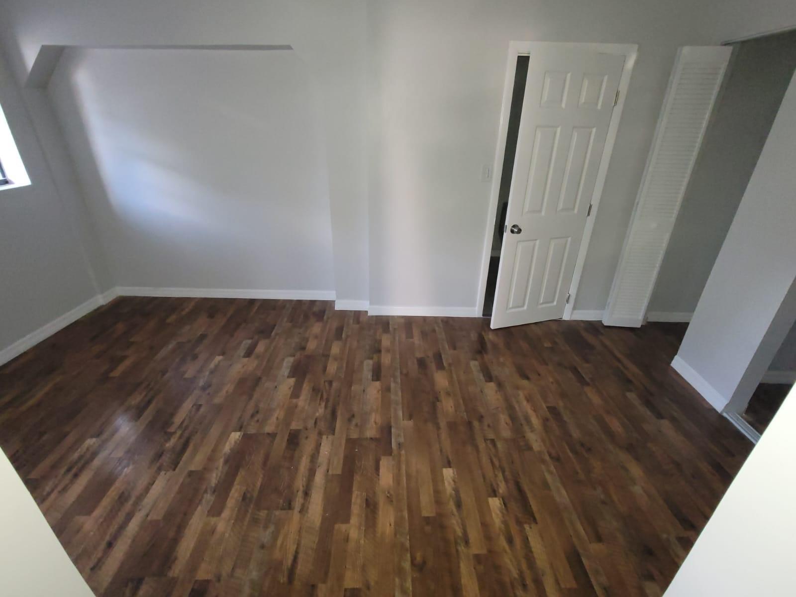 An empty room with wood-look flooring, white walls, a window, and an open door — 31 Edmund Road # 5, West Park FL 33023, WEST PARK, FL