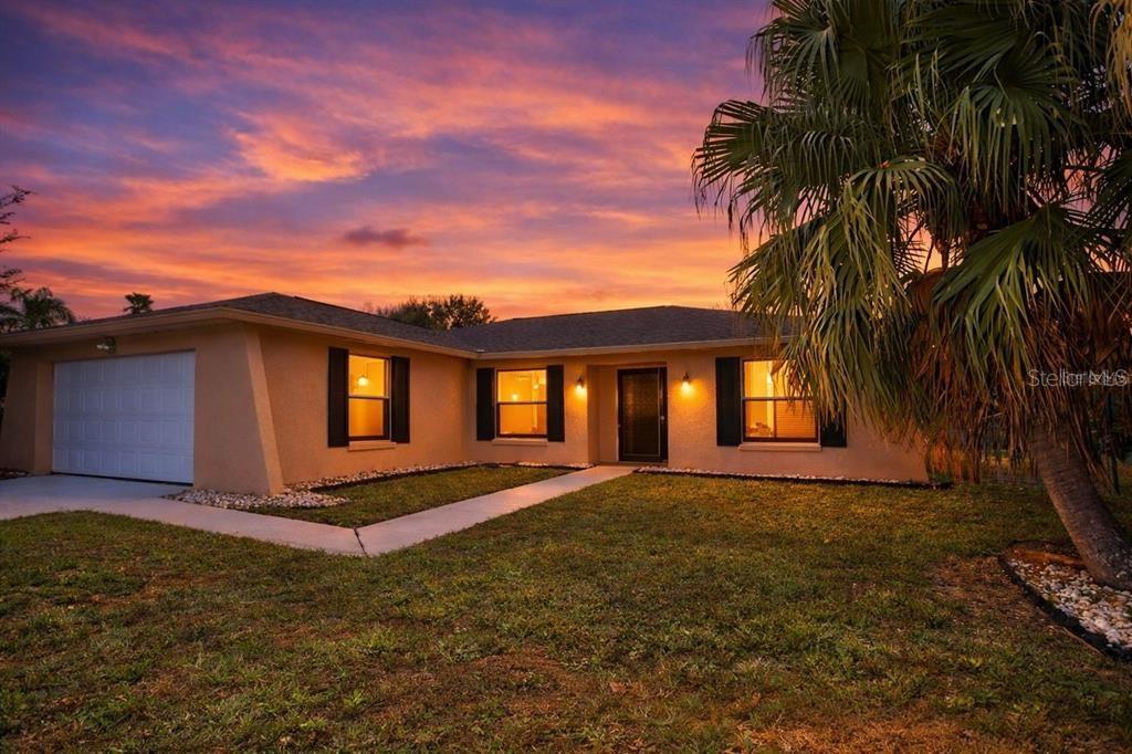 A single-story house with a garage and a palm tree at sunset — 620 HERALDO COURT, KISSIMMEE, FL