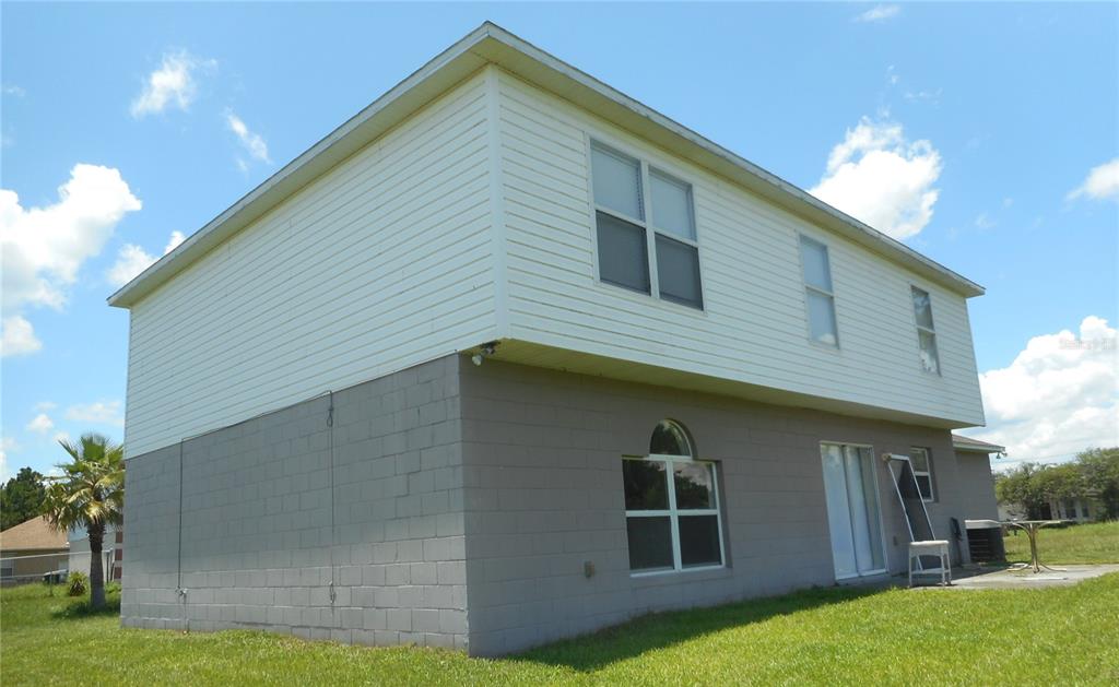A two-story house with a white vinyl-sided upper level and a gray concrete block base — 950 DERBYSHIRE DRIVE, KISSIMMEE, FL