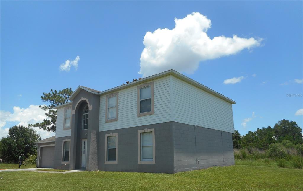 A two-story house with a gray stucco lower level and white siding on the upper level — 950 DERBYSHIRE DRIVE, KISSIMMEE, FL