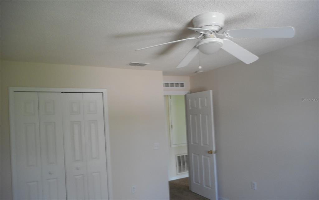 A bedroom features a white ceiling fan, a closet with bifold doors, and an open doorway — 950 DERBYSHIRE DRIVE, KISSIMMEE, FL
