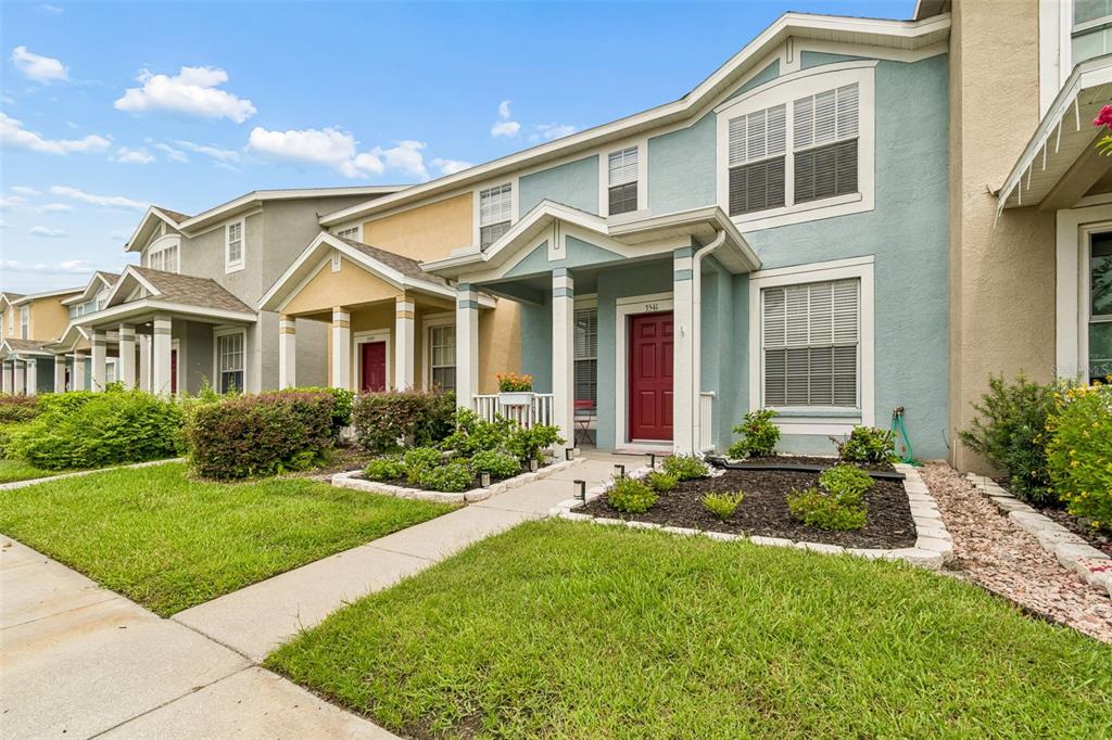 A blue two-story townhouse with a red front door and a small front yard — 3541 RED ROCK DRIVE, LAND O LAKES, FL