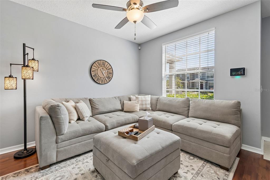 A living room features a large gray sectional sofa, a matching ottoman, and a ceiling fan — 3541 RED ROCK DRIVE, LAND O LAKES, FL