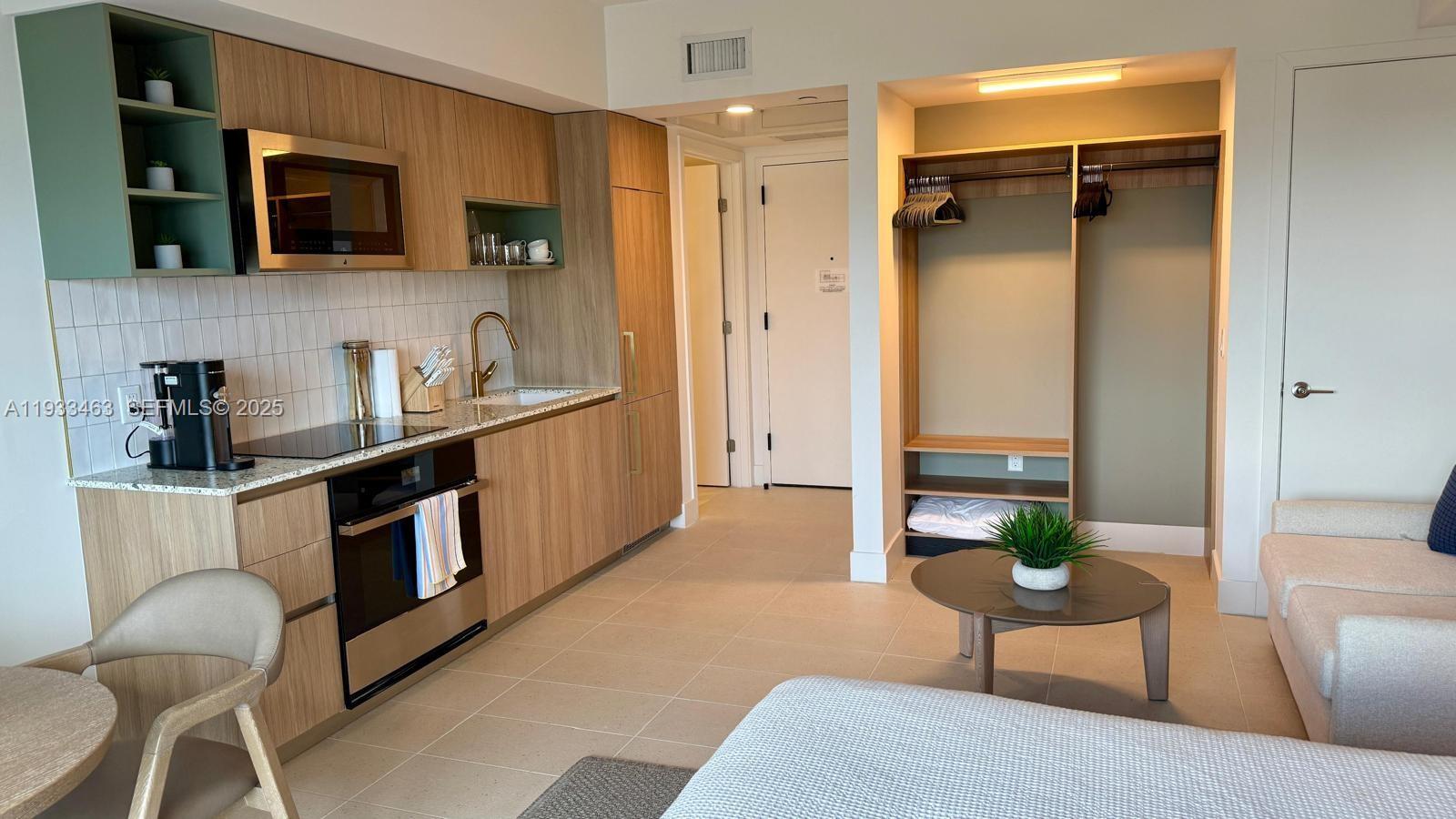 A studio apartment features a kitchenette with wood cabinets, stainless appliances, and an open closet — 159 NE 6th St # 4010, Miami FL 33132, MIAMI, FL
