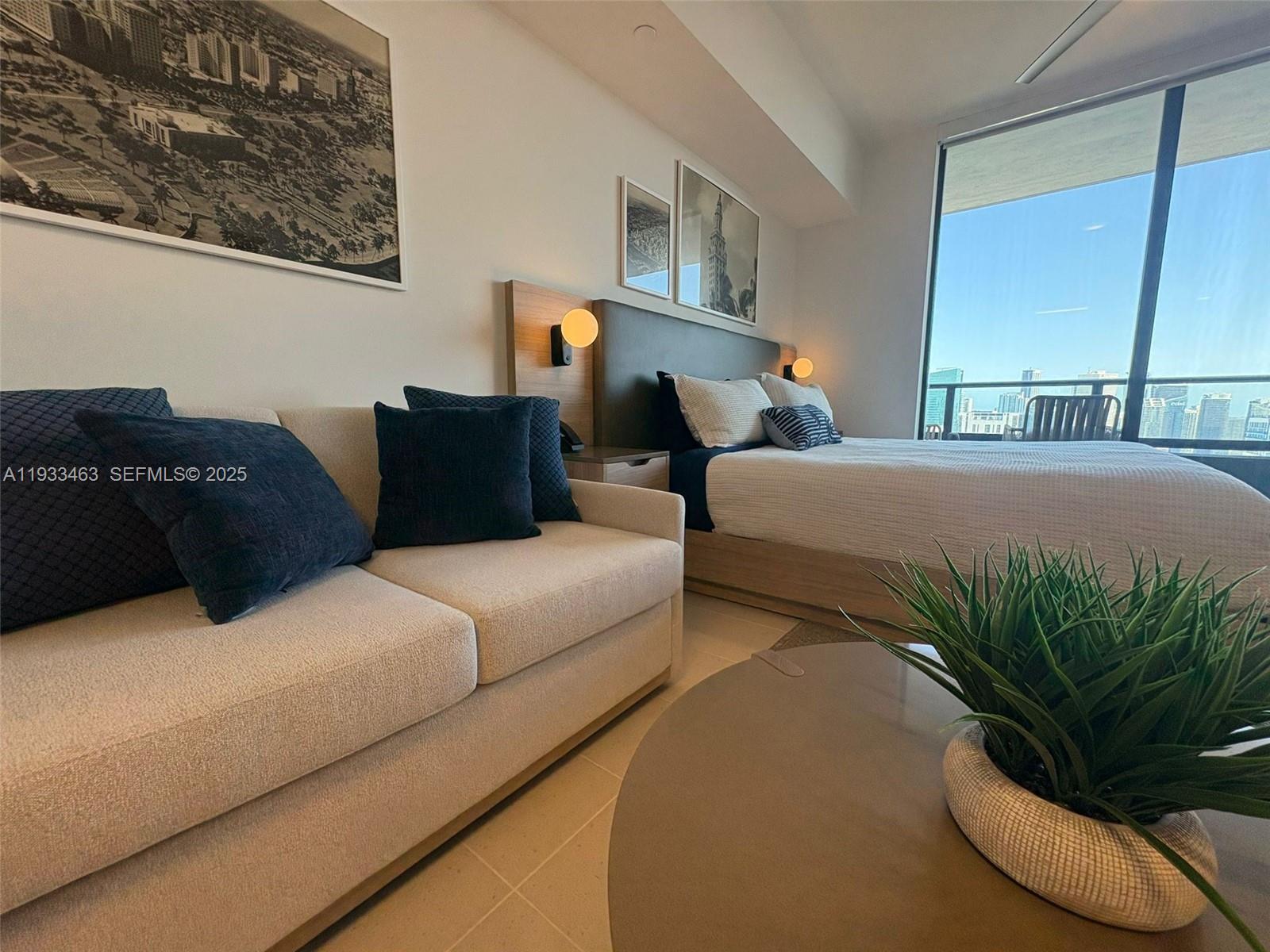 A bedroom features a sofa, a bed with a headboard, and a view of city buildings — 159 NE 6th St # 4010, Miami FL 33132, MIAMI, FL