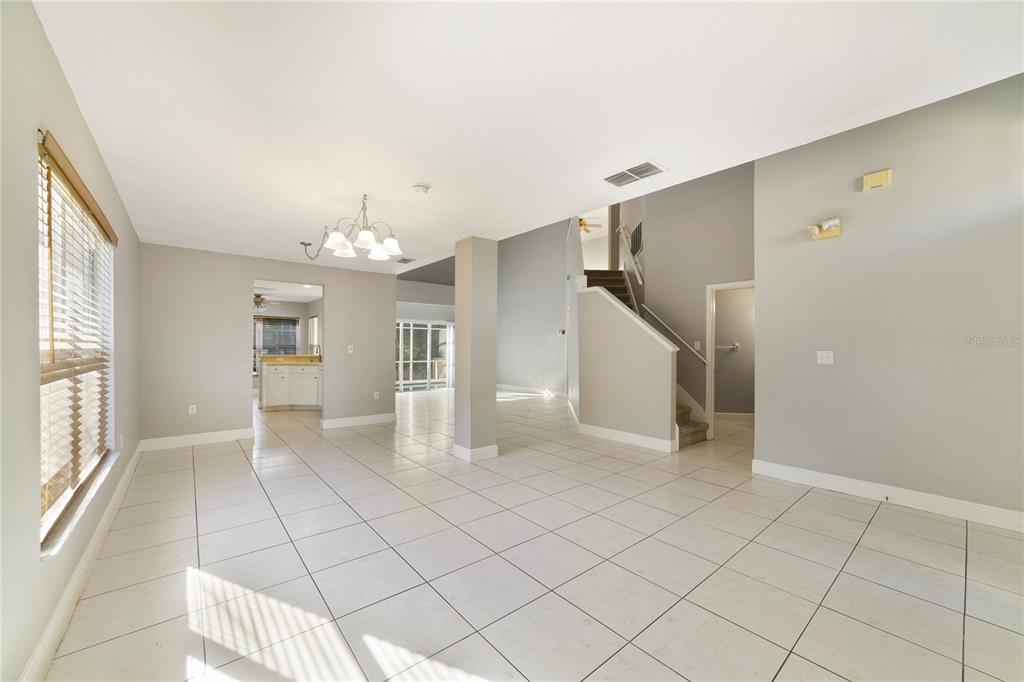 An open-concept living area features light gray walls, white tile flooring, and a staircase — 168 IMPERIAL OAK COURT, DAVENPORT, FL