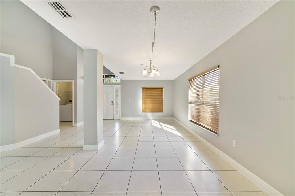 A bright, open-concept room features white tile flooring, light gray walls, and a hanging chandelier — 168 IMPERIAL OAK COURT, DAVENPORT, FL