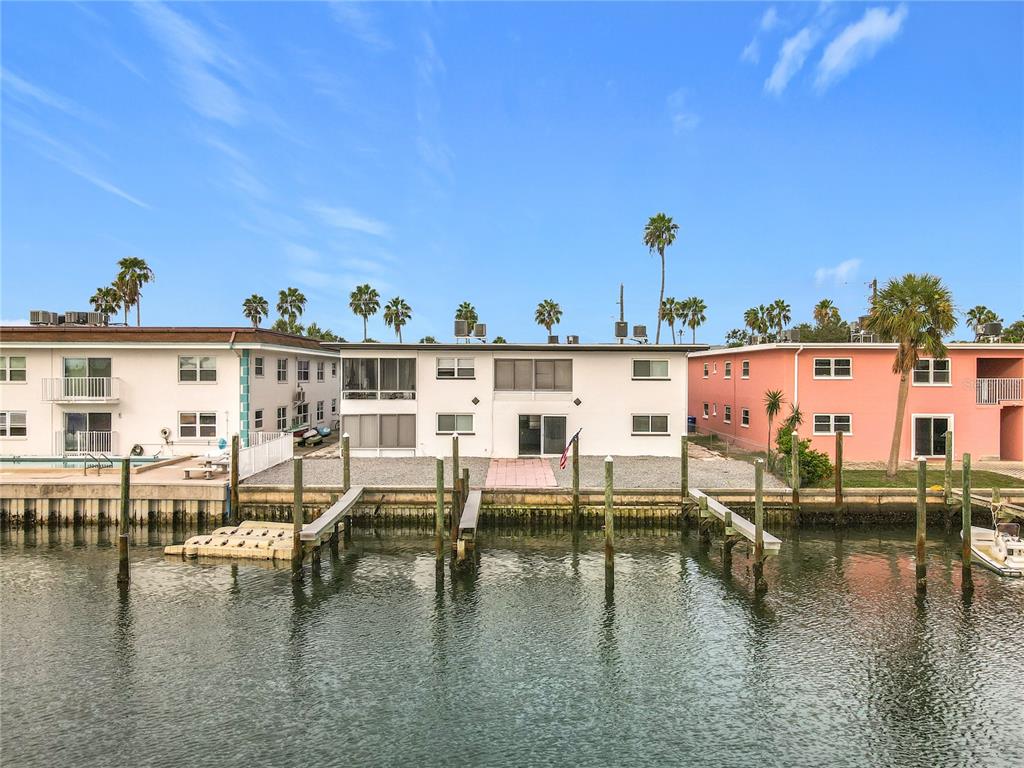 An exterior view of a multi-story apartment building with boat docks along a canal — 11705 3RD STREET E UNIT 8, TREASURE ISLAND, FL