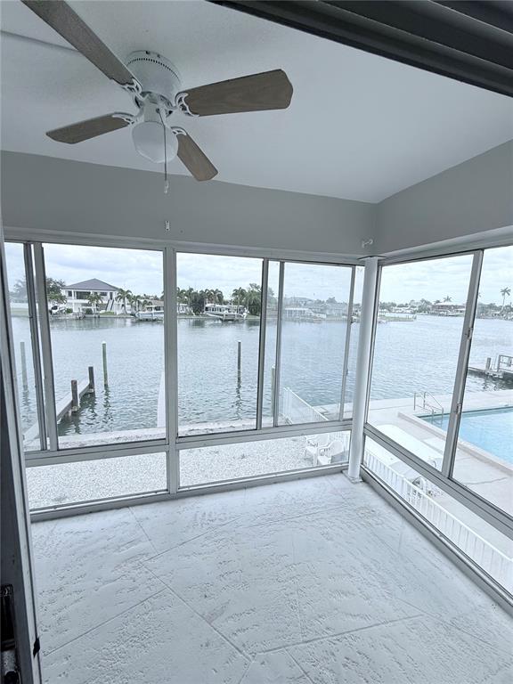A sunroom with a ceiling fan, tiled floor, and large windows overlooking a canal — 11705 3RD STREET E UNIT 8, TREASURE ISLAND, FL