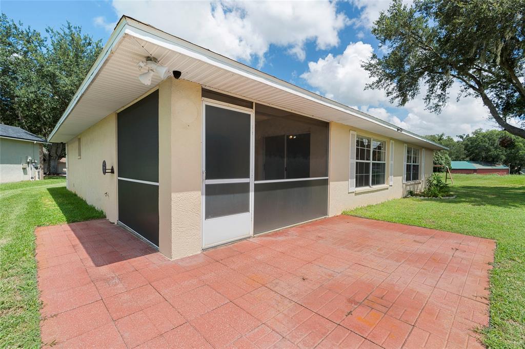 A red brick patio sits outside a house with a screened-in porch and white siding — 6412 LAURELWOOD DRIVE, ZEPHYRHILLS, FL