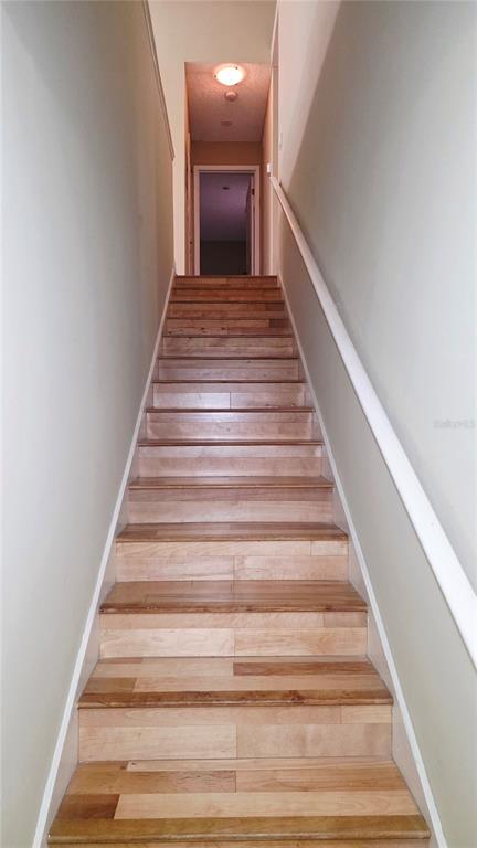 A straight wooden staircase leads upward toward a doorway at the top of the landing — 5416 E MICHIGAN STREET UNIT 6, ORLANDO, FL