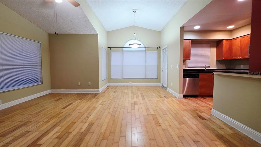 A living and dining area with hardwood floors, vaulted ceilings, and an adjacent kitchen — 5416 E MICHIGAN STREET UNIT 6, ORLANDO, FL