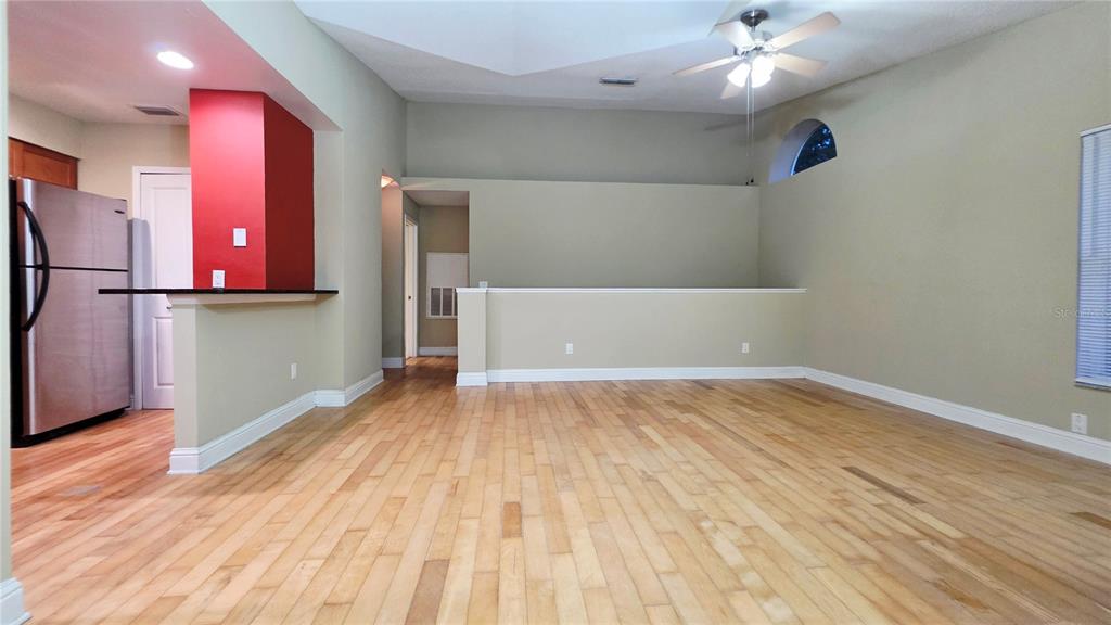 An open-concept room features light wood flooring, a vaulted ceiling, and a kitchen area — 5416 E MICHIGAN STREET UNIT 6, ORLANDO, FL