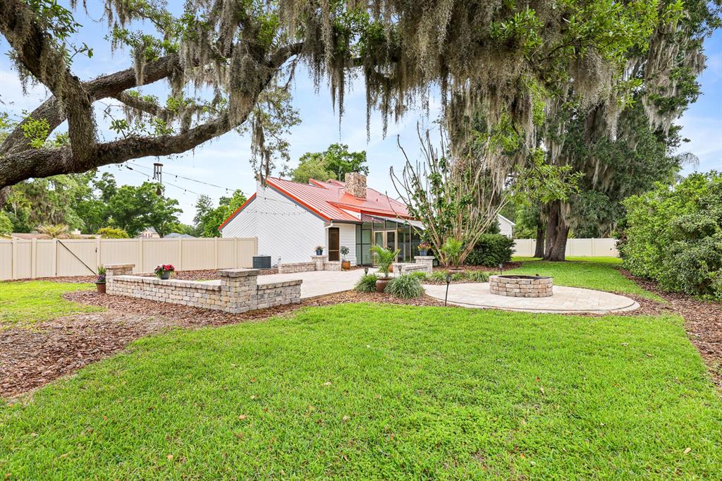 A backyard features a patio with a stone fire pit and a white house exterior — 2925 CHELSEA WOODS DRIVE, VALRICO, FL