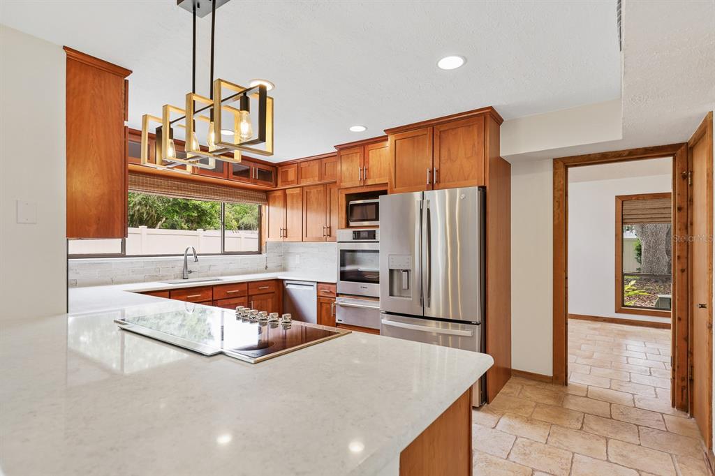 A kitchen features wood cabinets, stainless steel appliances, a white countertop, and a pendant light — 2925 CHELSEA WOODS DRIVE, VALRICO, FL