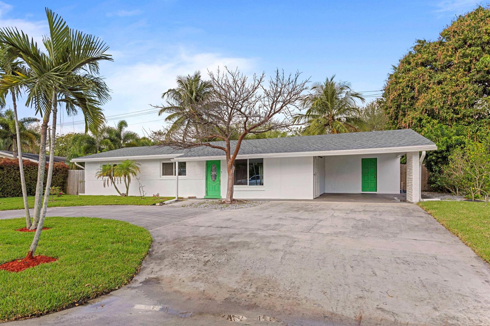 A white single-story house with a green front door and a carport under a blue sky — 2861 SW 9th Street, Boynton Beach FL 33435, BOYNTON BEACH, FL