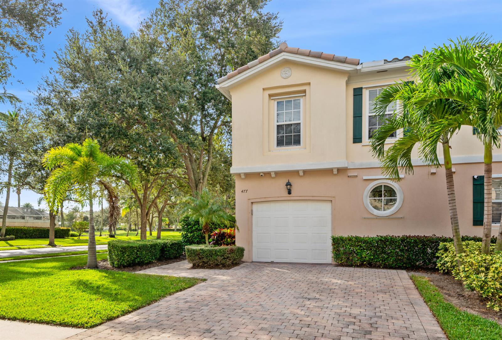 A two-story stucco house with a paved driveway, a single-car garage, and palm trees — 477 Capistrano Drive, Palm Beach Gardens FL 33410, PALM BEACH GARDENS, FL