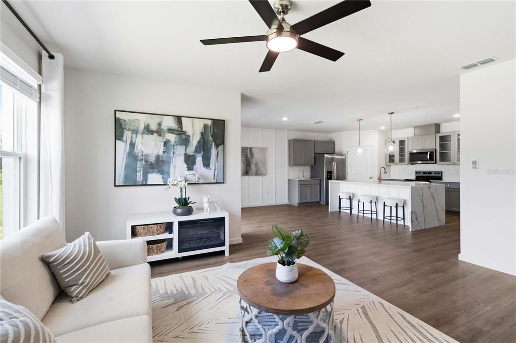 A living room with a sofa and coffee table opens into a kitchen with island seating — 1041 CHAMPION RDG DRIVE, DAYTONA BEACH, FL