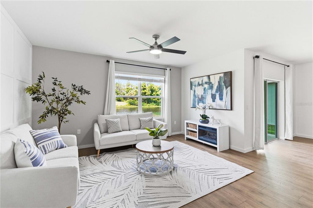 A living room features light gray walls, a white sofa, a patterned rug, and a ceiling fan — 1041 CHAMPION RDG DRIVE, DAYTONA BEACH, FL