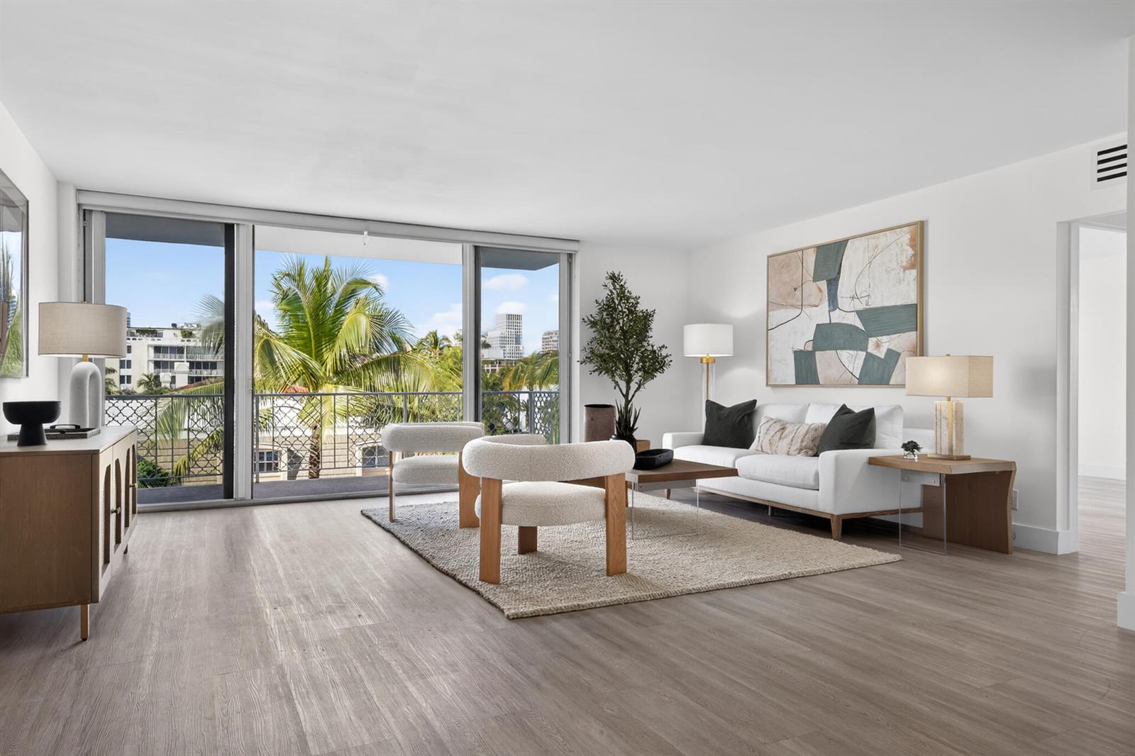 A bright living room features light wood flooring, modern furniture, and a balcony with palm trees — 354 Chilean Avenue # 4d, Palm Beach FL 33480, PALM BEACH, FL
