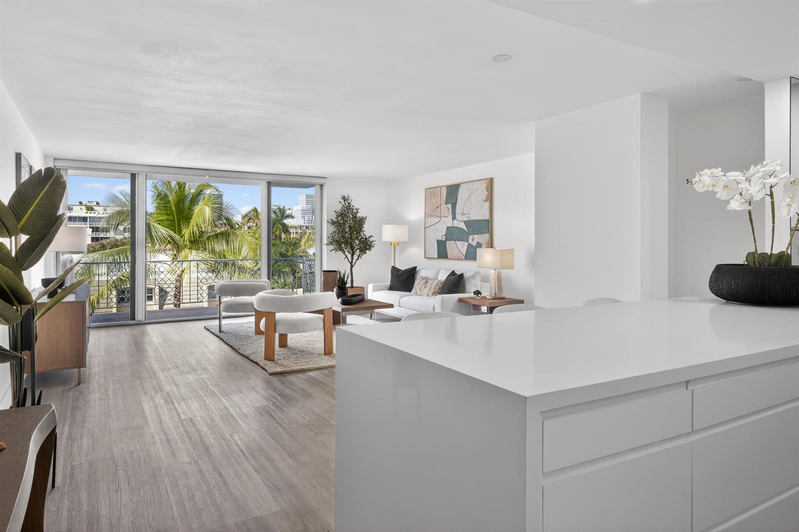 A bright living room with white walls, light wood flooring, and a balcony with palm trees — 354 Chilean Avenue # 4d, Palm Beach FL 33480, PALM BEACH, FL