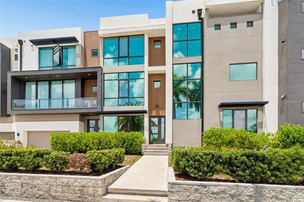 A modern three-story townhouse with large windows, a balcony, and a landscaped front yard — 94 W DAVIS BLVD., TAMPA, FL