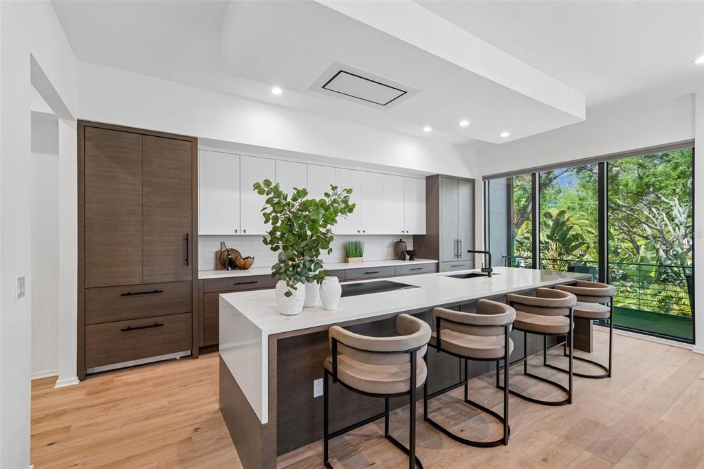 A modern kitchen features a large white island, dark wood cabinetry, and floor-to-ceiling windows — 94 W DAVIS BLVD., TAMPA, FL