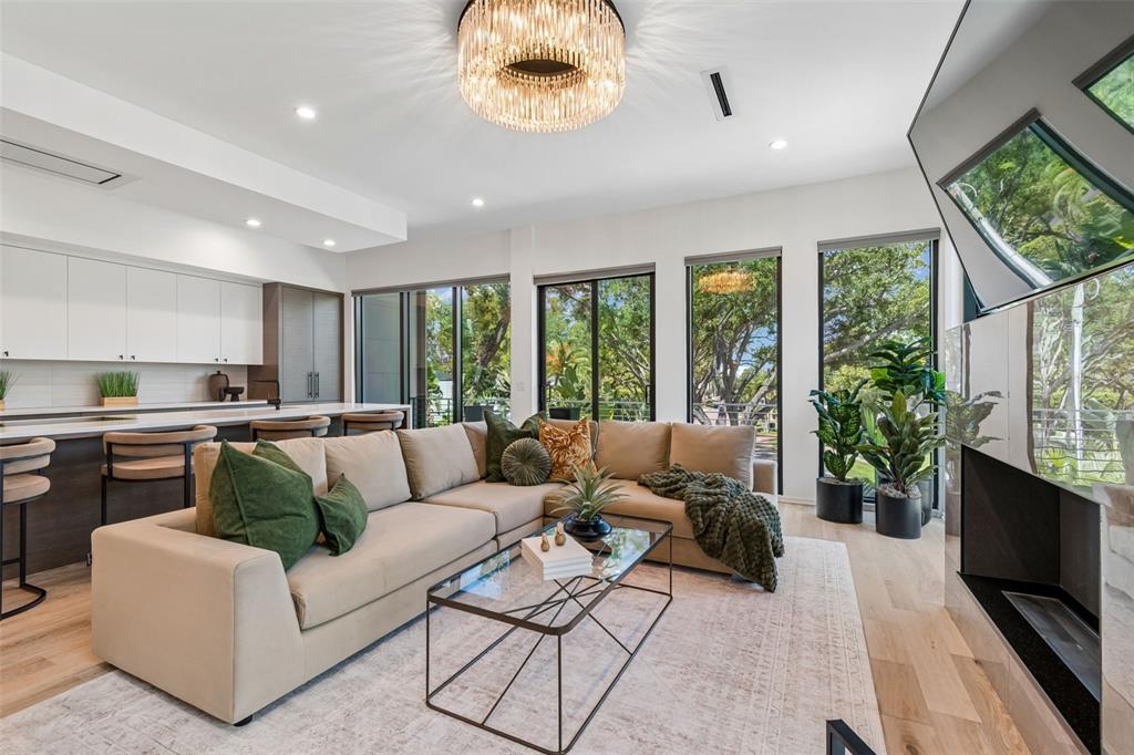 A modern living room features a beige sectional sofa, glass coffee table, and large windows — 94 W DAVIS BLVD., TAMPA, FL