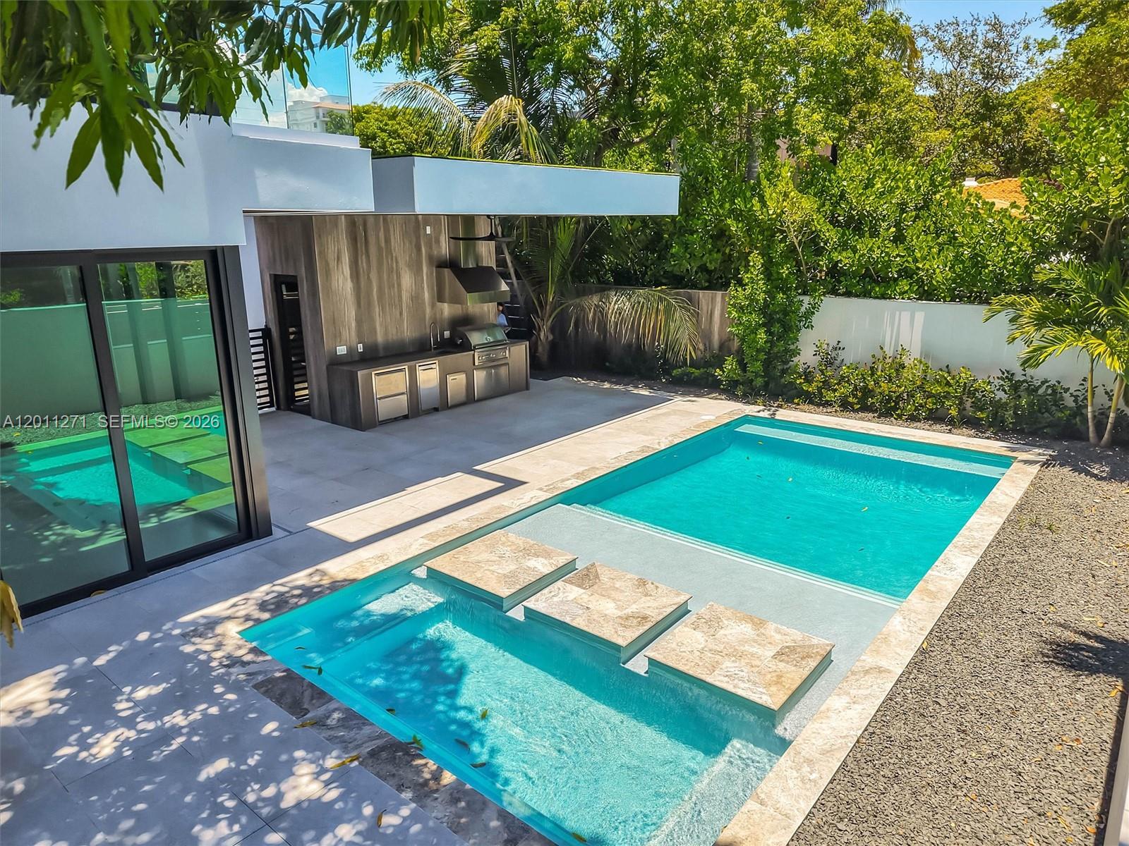 A modern outdoor patio features a built-in kitchen, a swimming pool, and stone stepping pads — 125 SW 29th Rd, Miami FL 33129, MIAMI, FL