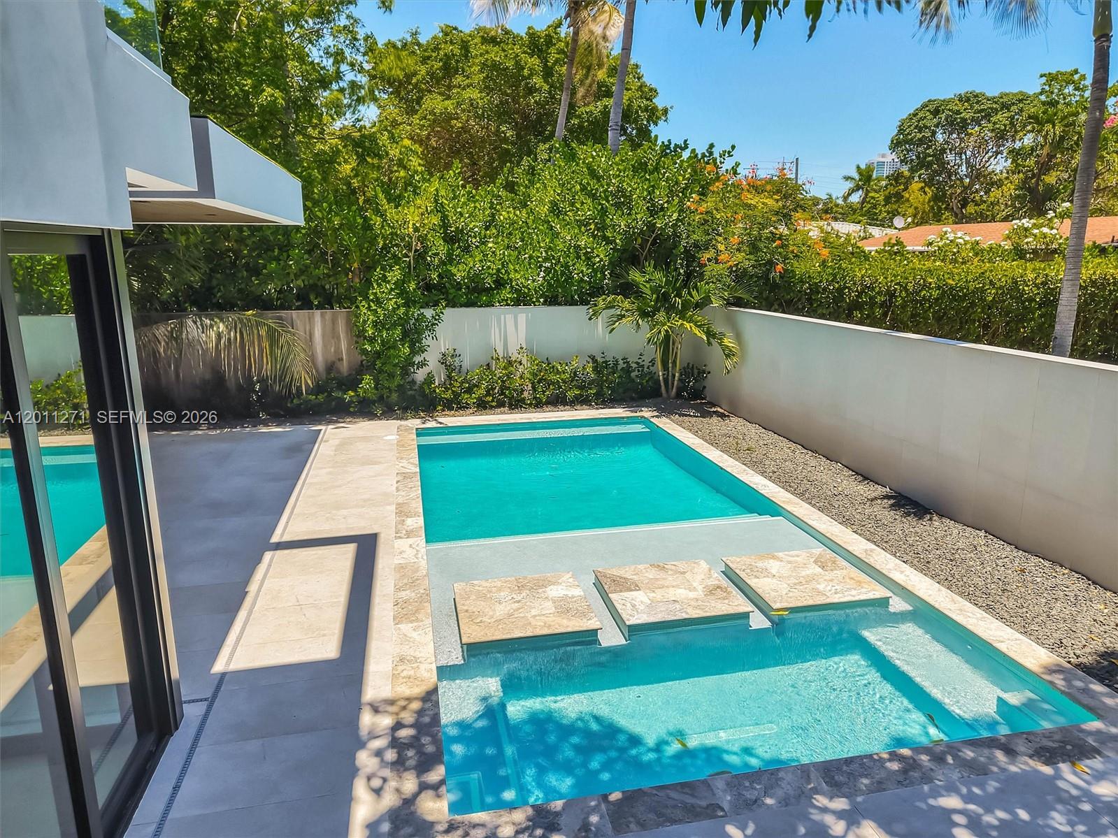A rectangular swimming pool with a shallow tanning ledge and stone stepping pads outdoors — 125 SW 29th Rd, Miami FL 33129, MIAMI, FL