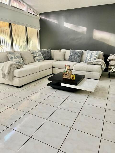 A living room features a large beige sectional sofa, a two-tiered coffee table, and tile flooring — 1453 White Pine Drive, Wellington FL 33414, WELLINGTON, FL