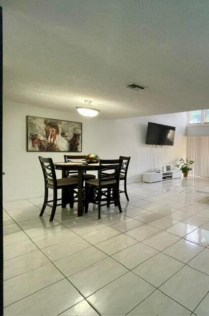 A dining area with a dark wood table and chairs sits on white tiled floors — 1453 White Pine Drive, Wellington FL 33414, WELLINGTON, FL