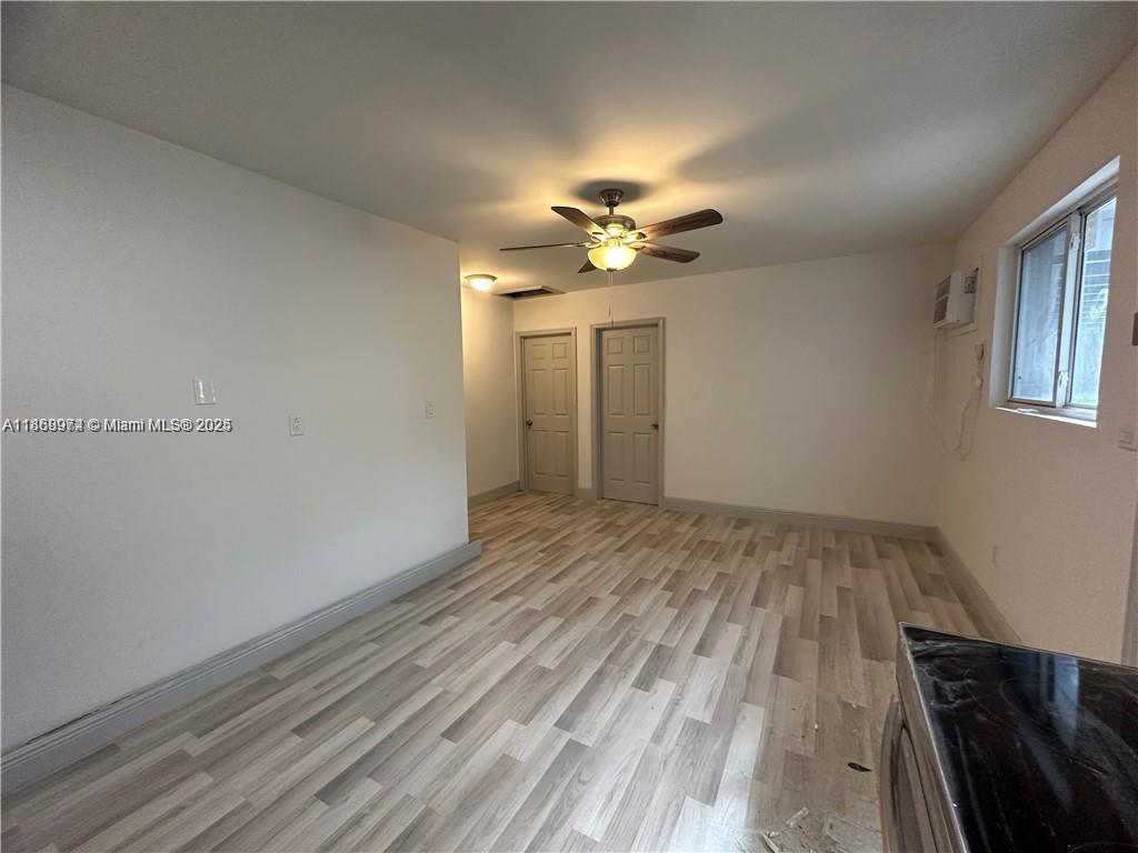 An interior room features light wood-look flooring, white walls, a ceiling fan, and two closed doors — 1255 NE 110th Ter, Miami FL 33161, MIAMI, FL