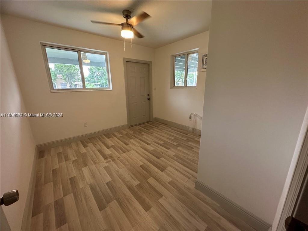 An empty room features light wood-look flooring, a ceiling fan, and two windows — 1255 NE 110th Ter, Miami FL 33161, MIAMI, FL