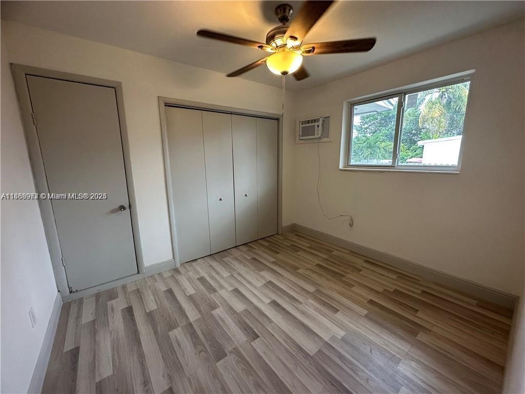 This bedroom features light wood-look flooring, a ceiling fan, a closet, and a window unit — 1255 NE 110th Ter, Miami FL 33161, MIAMI, FL
