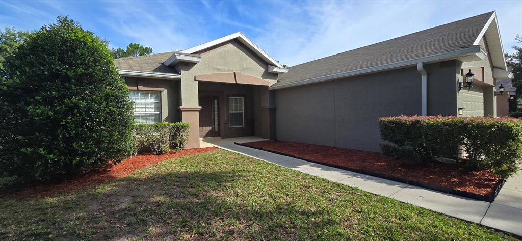 A single-story house with a gray stucco exterior, a covered entryway, and landscaped front yard — 4170 SW 47TH COURT, OCALA, FL