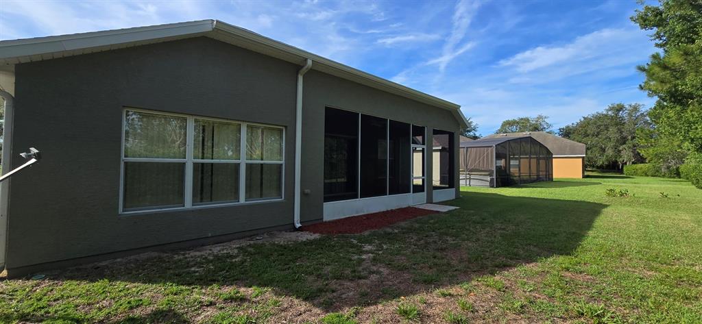 The exterior of a gray house features a screened-in porch and a large grassy yard — 4170 SW 47TH COURT, OCALA, FL