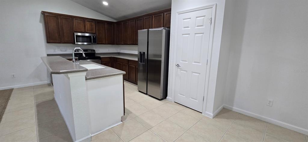 A kitchen features dark wood cabinets, stainless steel appliances, and a raised breakfast bar — 4170 SW 47TH COURT, OCALA, FL
