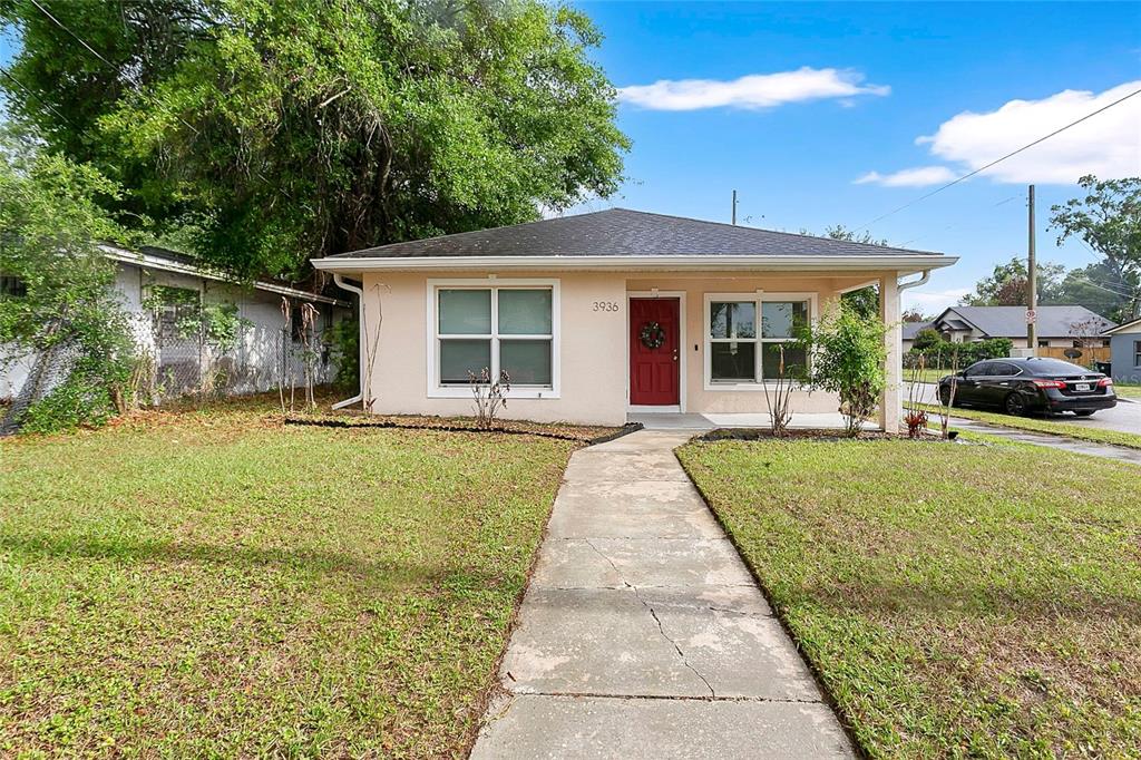 A single-story house with a beige exterior, red front door, and a concrete walkway — 3936 THOMAS STREET, ORLANDO, FL