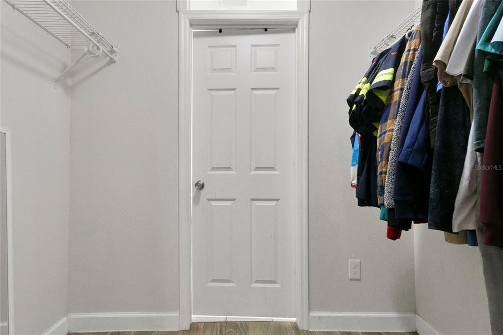 A walk-in closet features a white six-panel door, wire shelving, and hanging clothes — 3936 THOMAS STREET, ORLANDO, FL