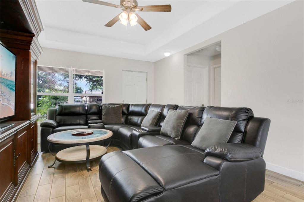 A living room features a large black sectional sofa, a coffee table, and wood-look flooring — 3936 THOMAS STREET, ORLANDO, FL