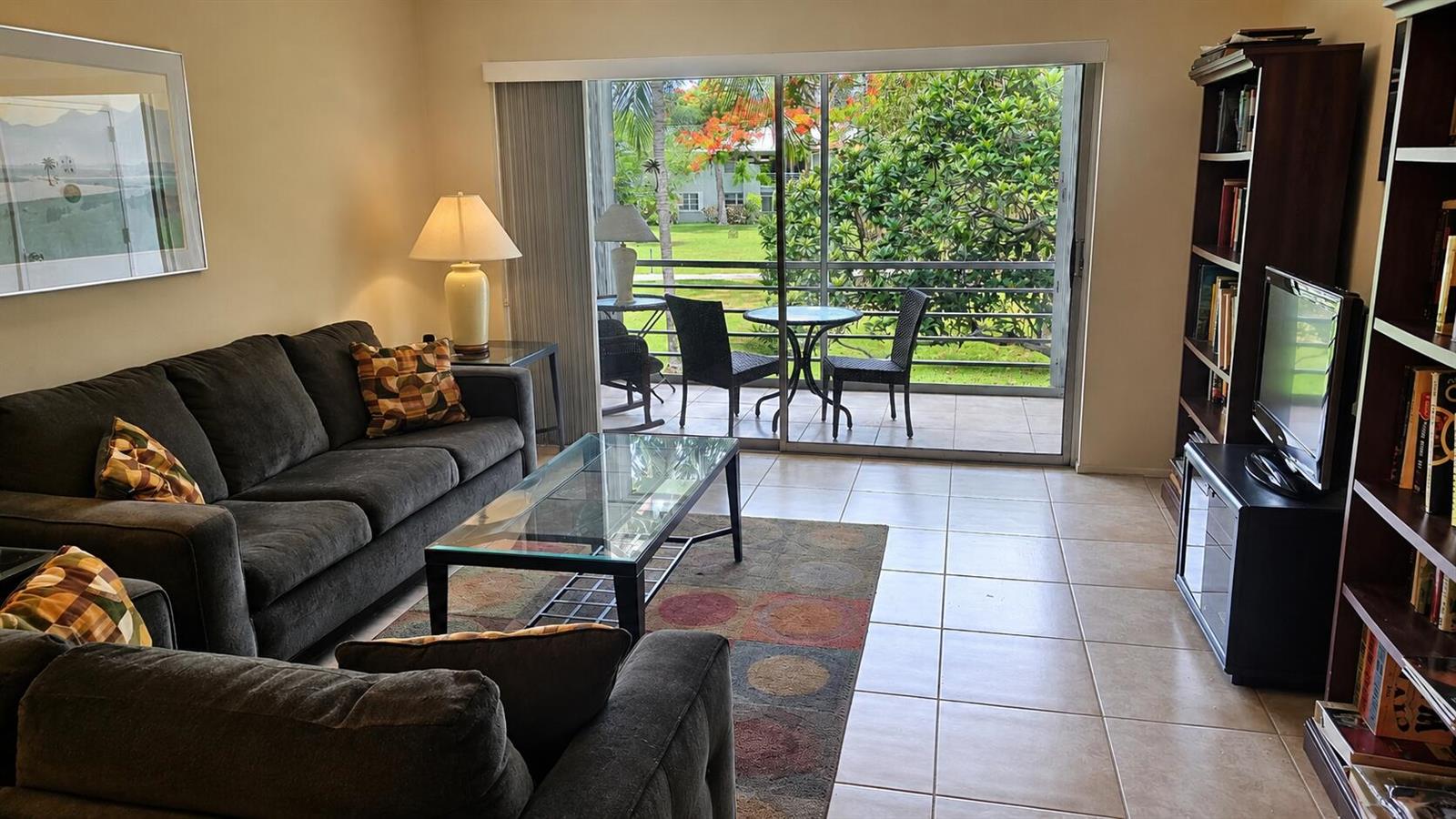 A living room with a dark sofa, glass coffee table, and sliding doors to a balcony — 2620 SW 22nd Avenue # 1004, Delray Beach FL 33445, DELRAY BEACH, FL