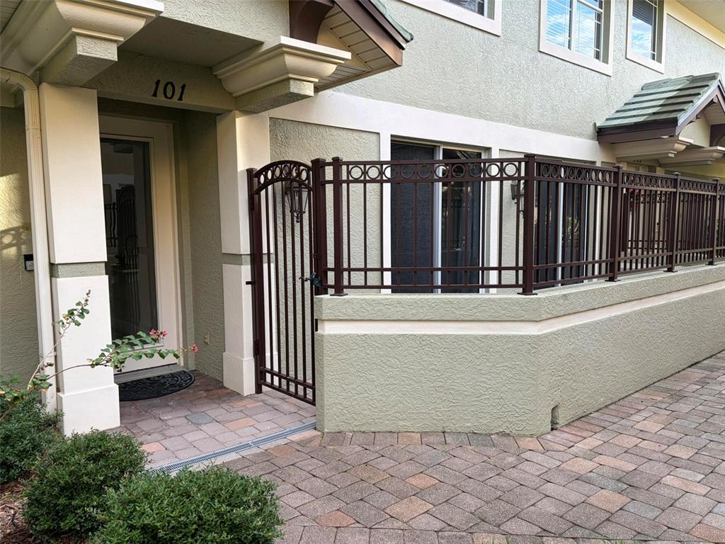 A brown metal gate and fence enclose a patio area next to a building entrance — 6536 MOORINGS POINT CIRCLE UNIT 101, LAKEWOOD RANCH, FL