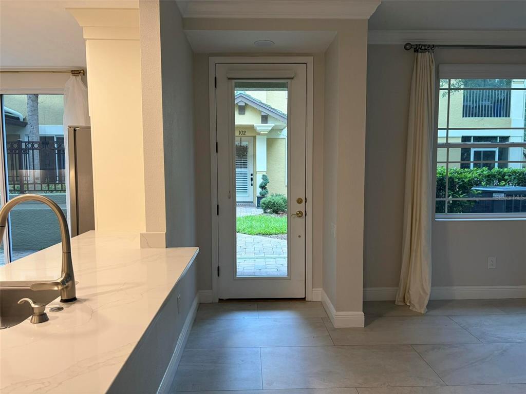 A kitchen with a white countertop and sink overlooks a glass door to the exterior — 6536 MOORINGS POINT CIRCLE UNIT 101, LAKEWOOD RANCH, FL